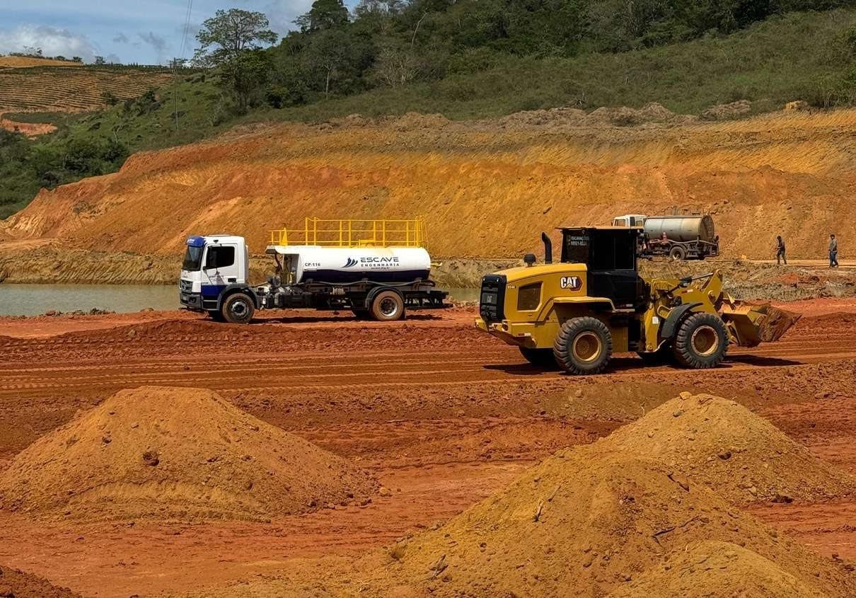 Caminhão-pipa e pá-carregadeira em frente de terraplenagem